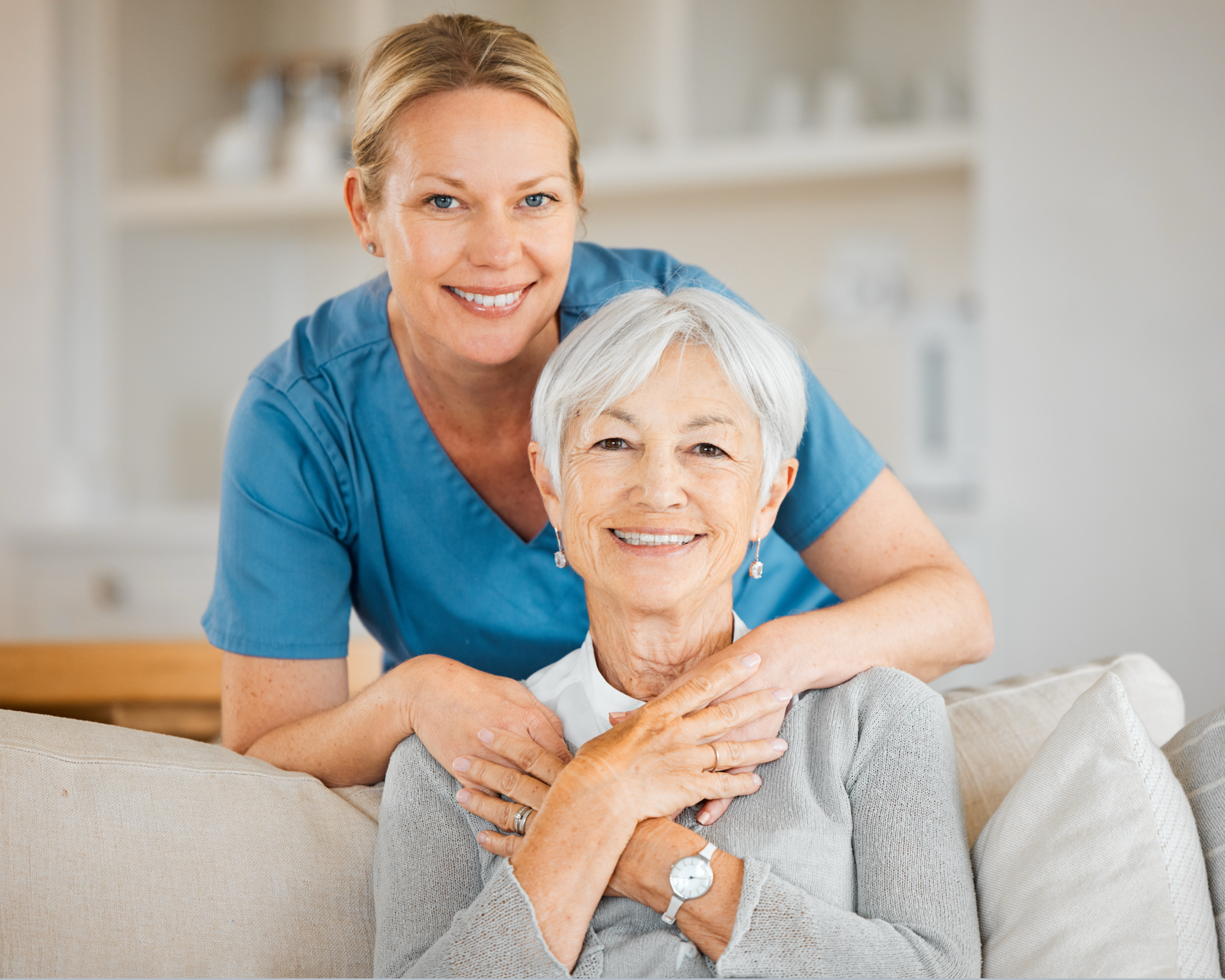 Persönliche Betreuung mit Herz Lächelnde Betreuungskraft steht hinter einer Seniorin in der Küche.