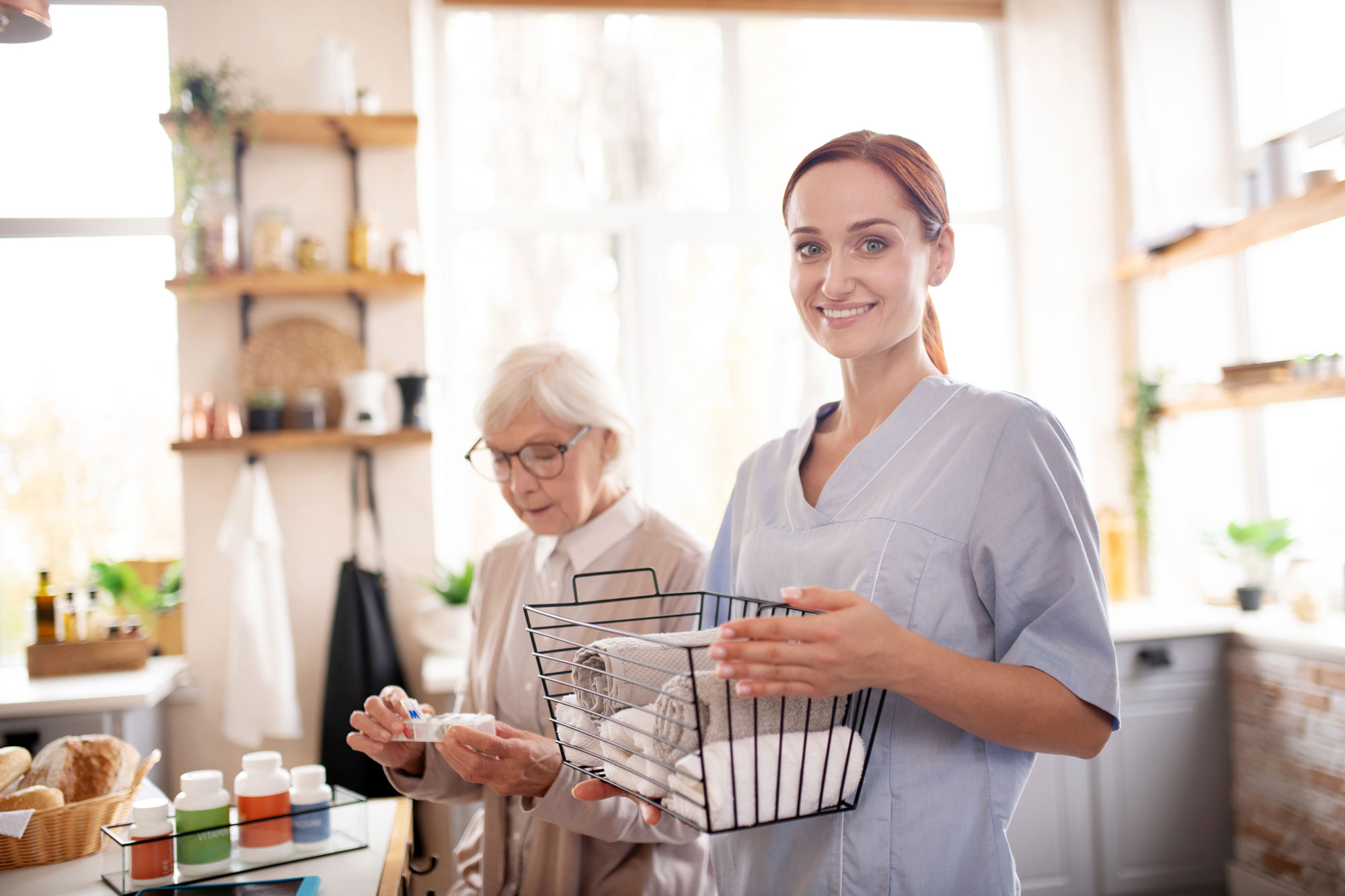 Unterstützung im eigenen Zuhause Betreuungskraft unterstützt eine Seniorin zu Hause am Tisch.